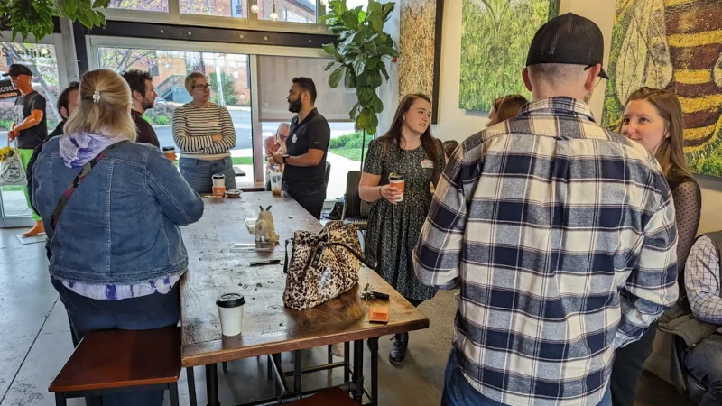 A group of 9 people around a table in a coffee shop talking about data